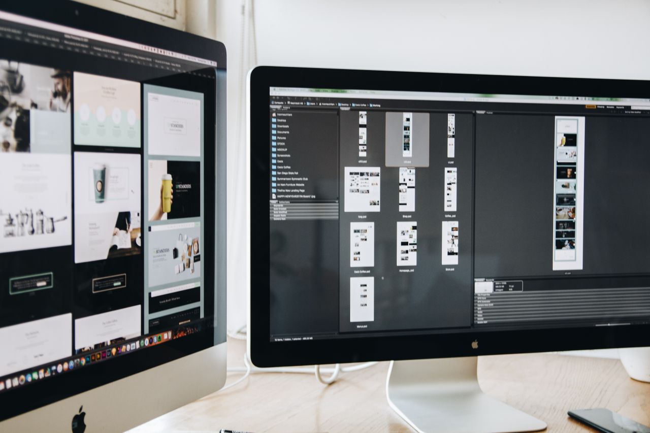 Un espace de travail moderne avec deux écrans d'ordinateur montrant des projets de conception web, mettant en avant la technologie et la productivité.